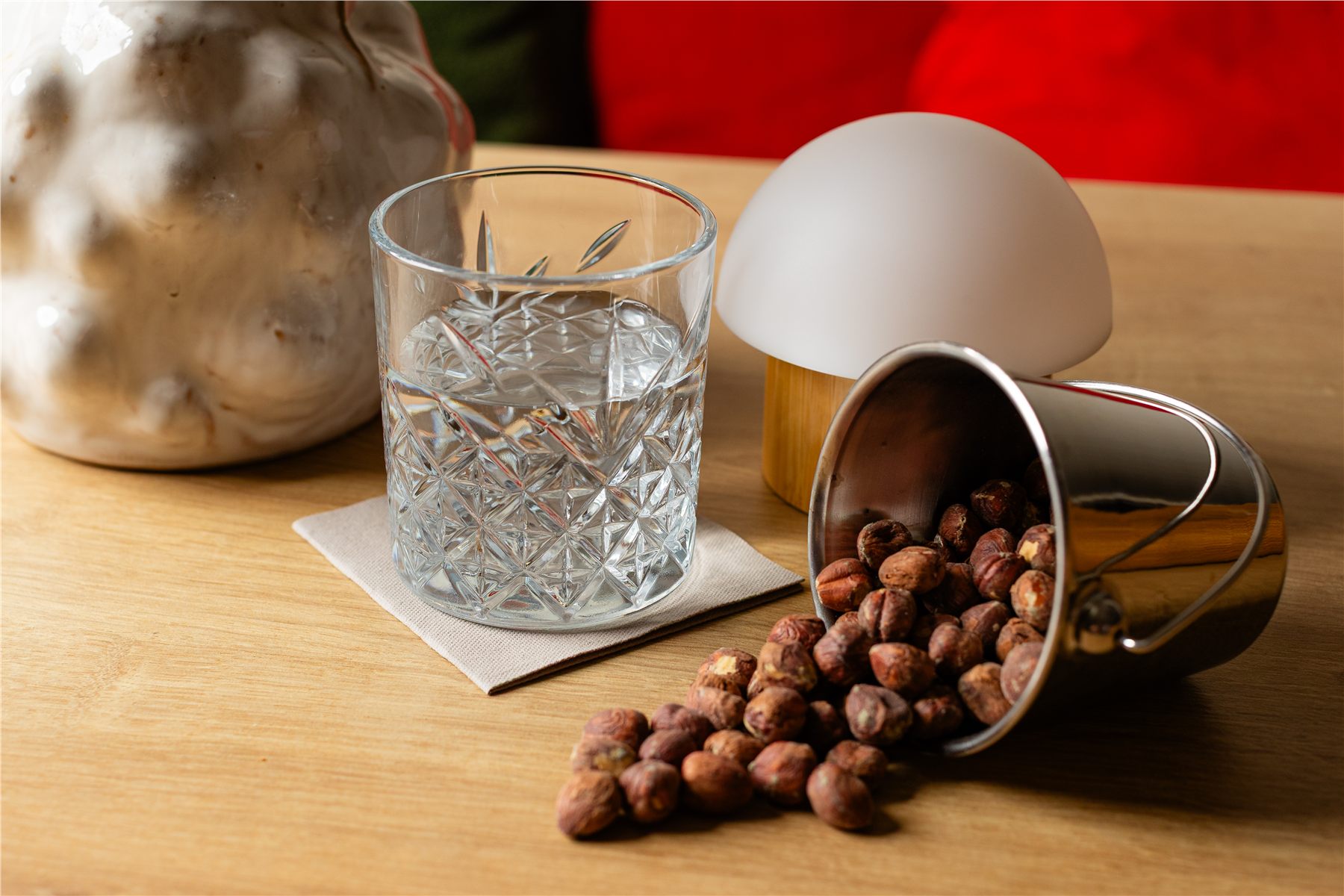 Cut crystal tumbler on a cream cocktail napkin with hazelnuts