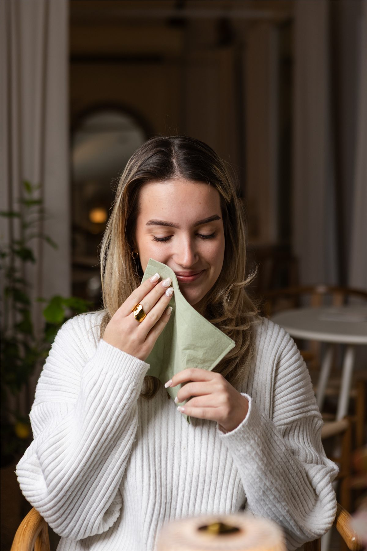 Guest holding a sage green napkin in a warmly lit dining room