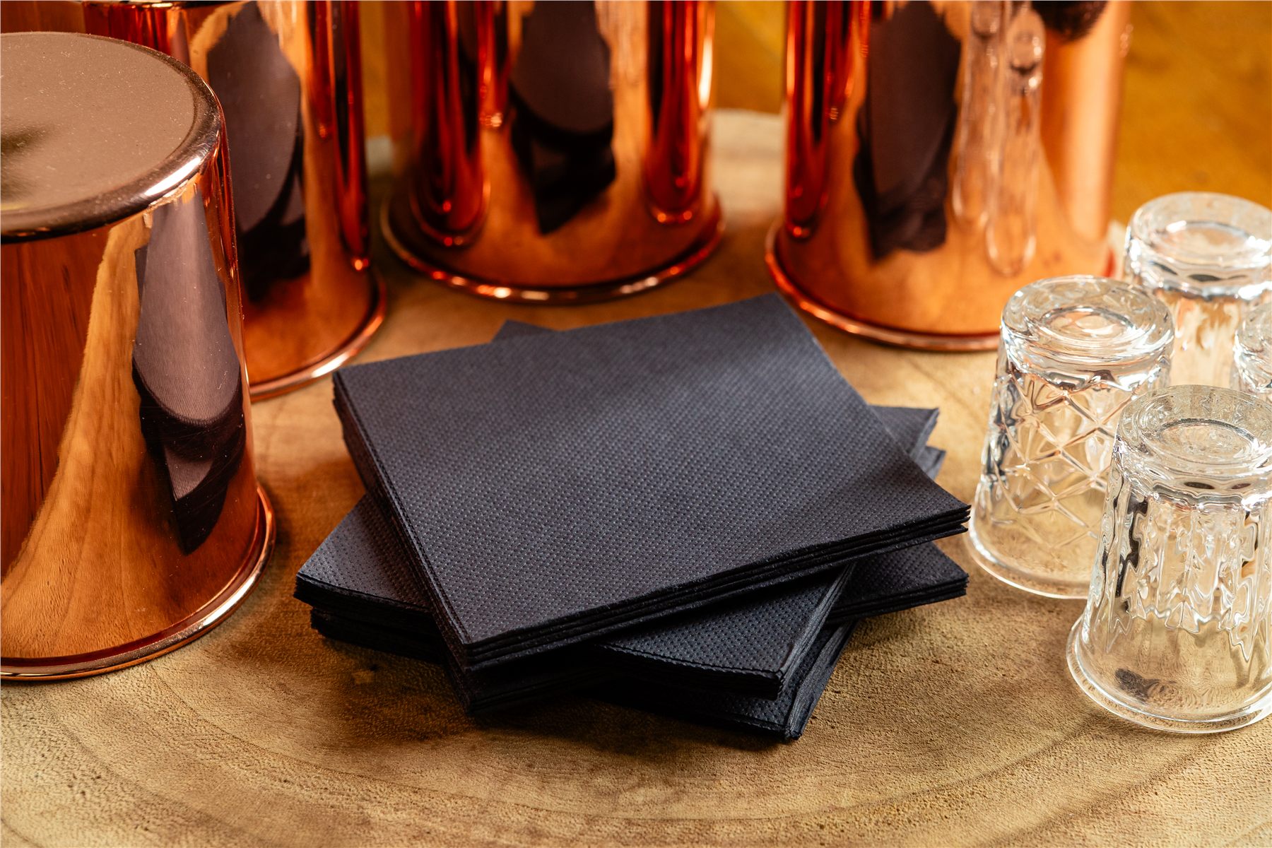 Stack of black napkins beside copper cocktail mugs