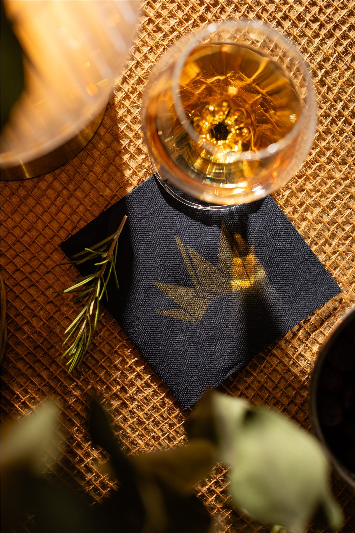 Overhead of a whiskey glass on a printed navy cocktail napkin