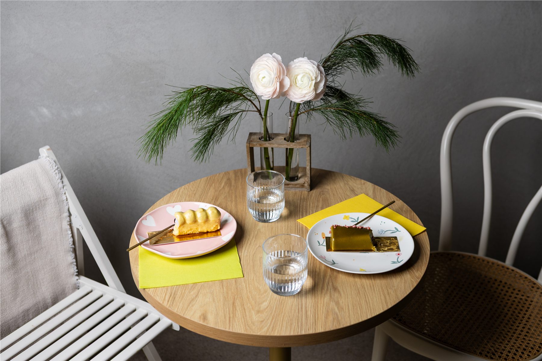 Café table with yellow napkins under two plated desserts